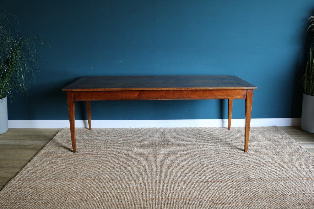 A nineteenth-century French farmhouse table constructed from warm brown cherry wood with tapered square legs and a rectangular plank top. View V