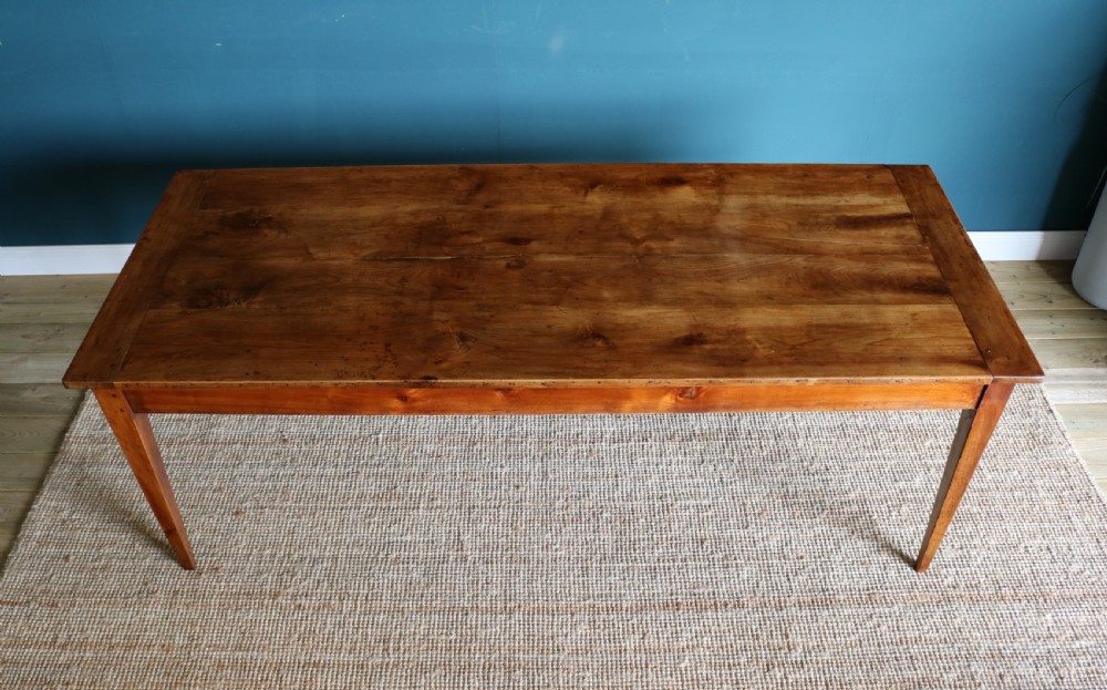 A nineteenth-century French farmhouse table constructed from warm brown cherry wood with tapered square legs and a rectangular plank top. View VII