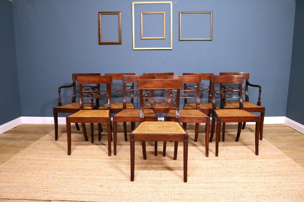 A set of ten Regency style mahogany dining chairs featuring hand-woven cane seats, tablet top rails, geometric carved splats, and two matching carver armchairs.
