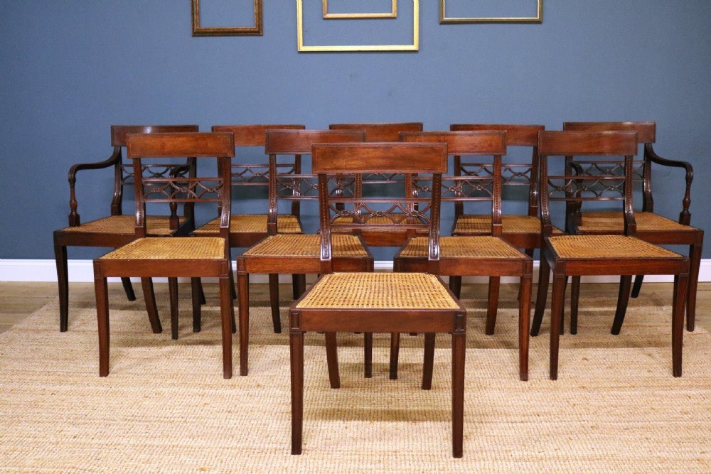 A set of ten Regency style mahogany dining chairs featuring hand-woven cane seats, tablet top rails, geometric carved splats, and two matching carver armchairs. View IV