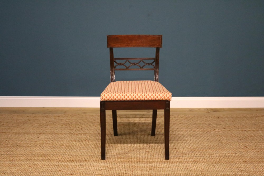 A set of ten Regency style mahogany dining chairs featuring hand-woven cane seats, tablet top rails, geometric carved splats, and two matching carver armchairs. View V