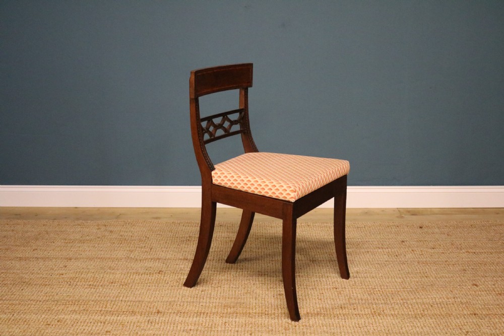A set of ten Regency style mahogany dining chairs featuring hand-woven cane seats, tablet top rails, geometric carved splats, and two matching carver armchairs. View VI