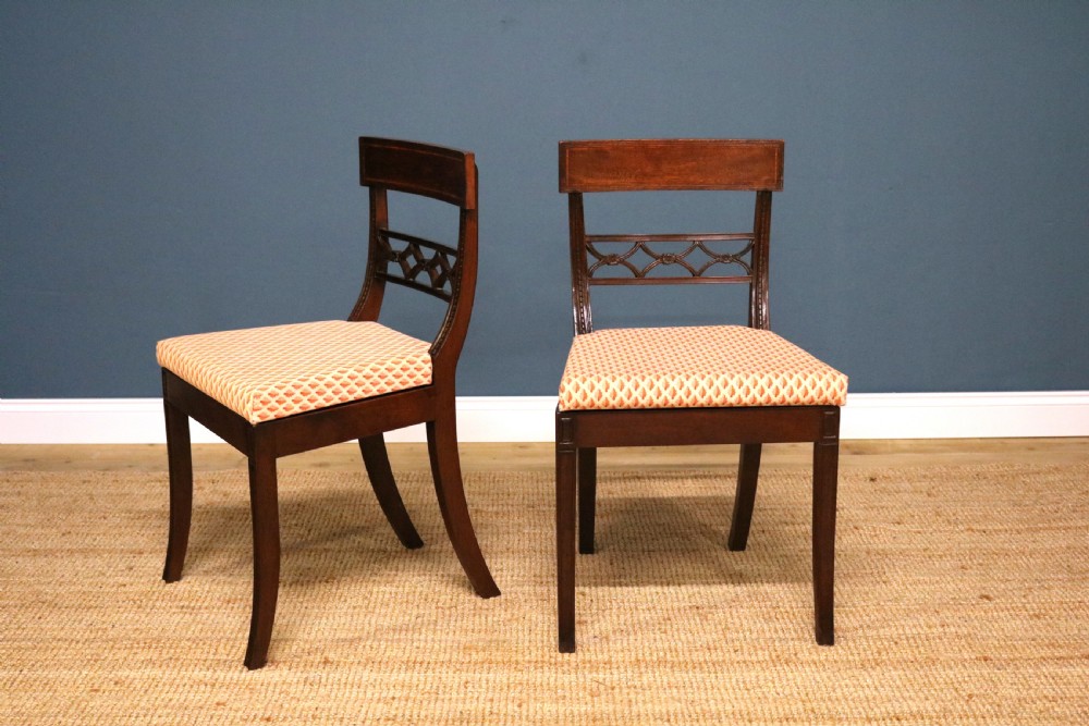 A set of ten Regency style mahogany dining chairs featuring hand-woven cane seats, tablet top rails, geometric carved splats, and two matching carver armchairs. View VII