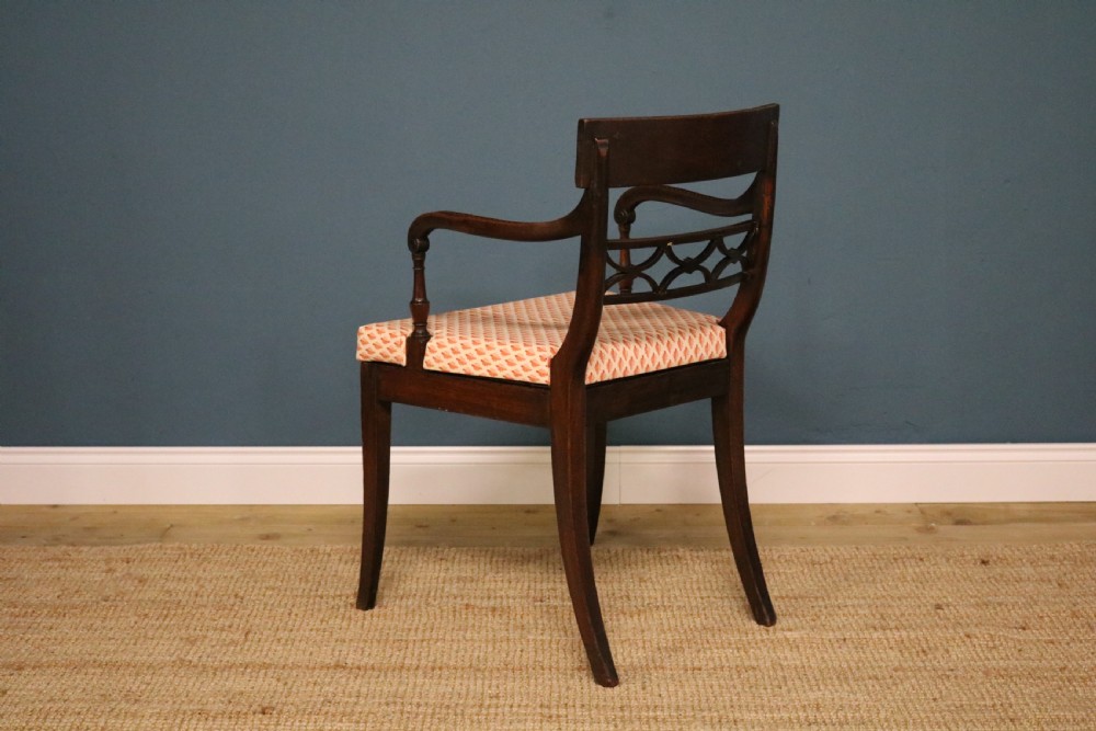 A set of ten Regency style mahogany dining chairs featuring hand-woven cane seats, tablet top rails, geometric carved splats, and two matching carver armchairs. View X