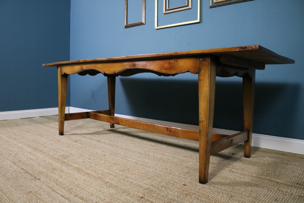 A long French cherry wood dining table featuring a scalloped apron, tapered legs, and a low stretcher base. View VI