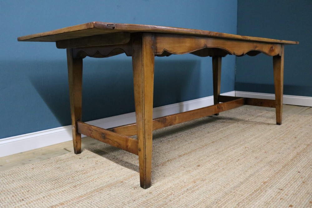 A long French cherry wood dining table featuring a scalloped apron, tapered legs, and a low stretcher base. View VII