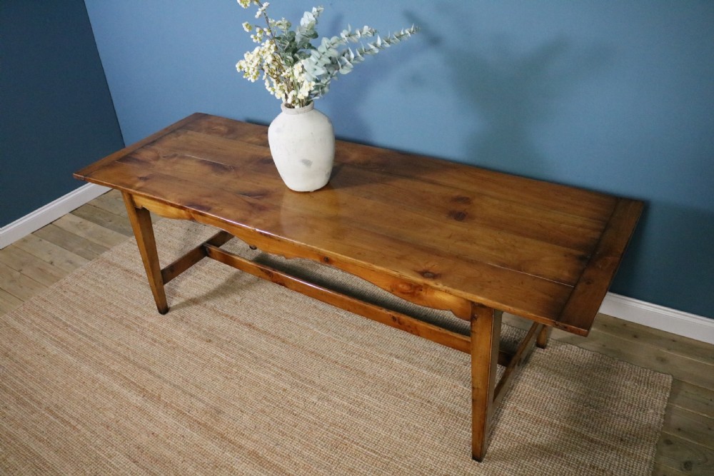 A long French cherry wood dining table featuring a scalloped apron, tapered legs, and a low stretcher base. View XI