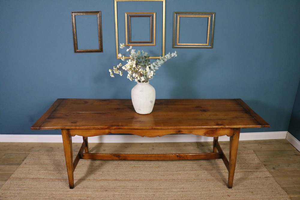 A long French cherry wood dining table featuring a scalloped apron, tapered legs, and a low stretcher base. View XII