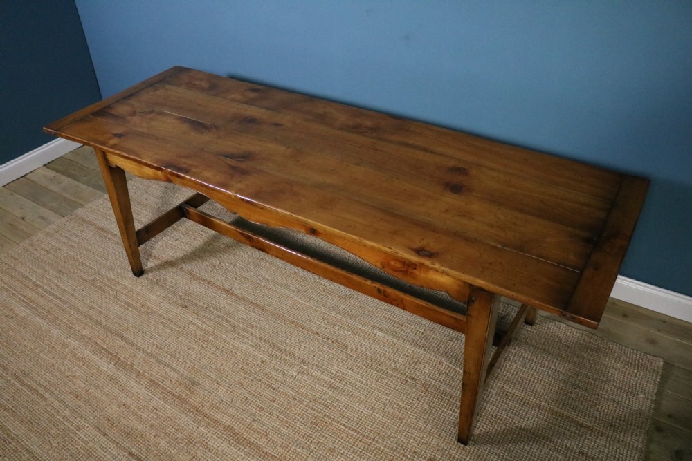 A long French cherry wood dining table featuring a scalloped apron, tapered legs, and a low stretcher base. View XIII