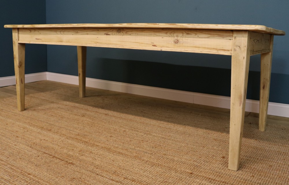 A long rectangular bleached pine dining table supported by four square tapered legs and a simple straight apron.