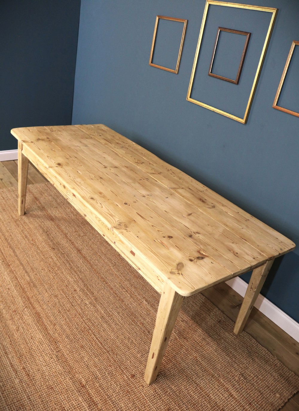 A long rectangular bleached pine dining table supported by four square tapered legs and a simple straight apron. View X