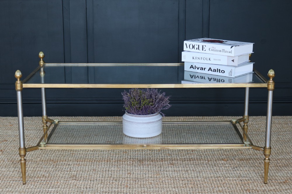 A two-tier rectangular brass and glass coffee table featuring finial corner posts and tapered legs.