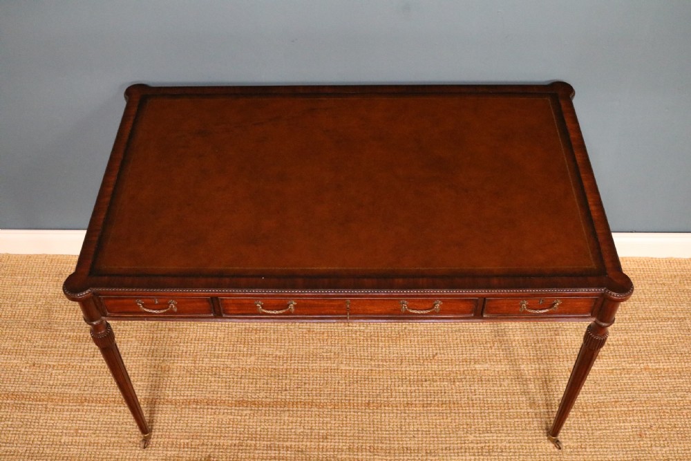 A George IV style mahogany writing table featuring frieze drawers with brass handles and reeded tapering legs on brass castors. View V