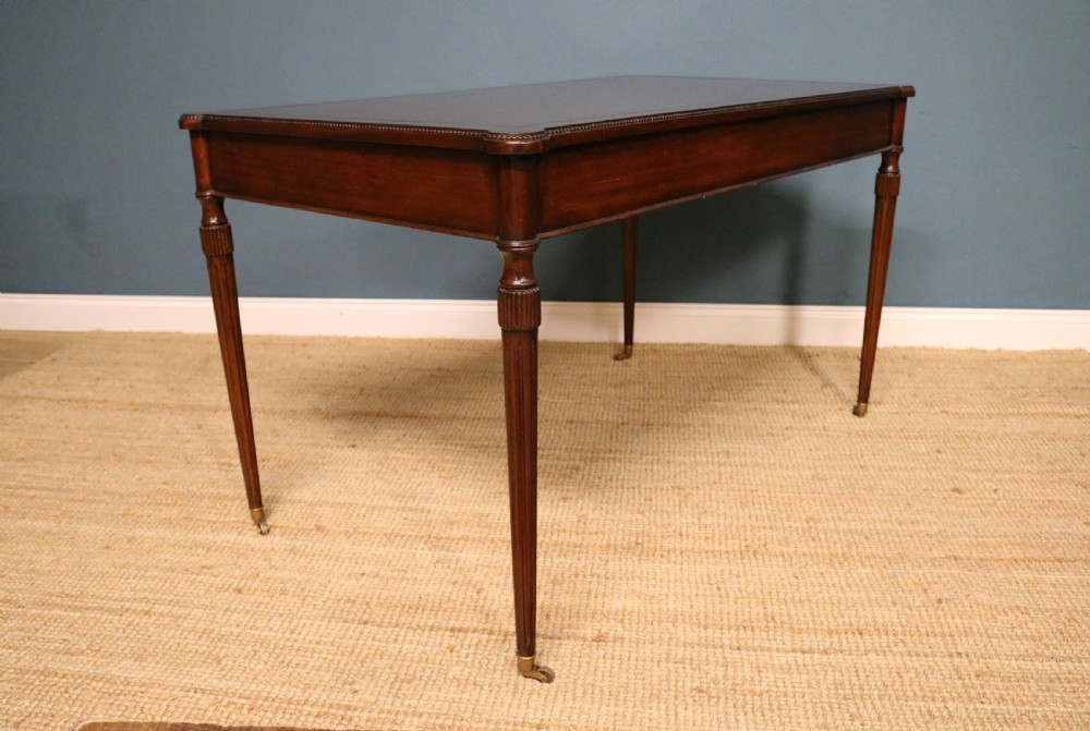 A George IV style mahogany writing table featuring frieze drawers with brass handles and reeded tapering legs on brass castors. View VI