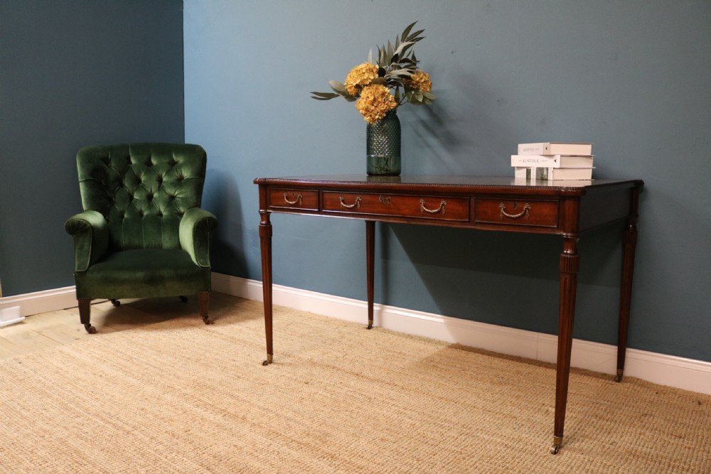A George IV style mahogany writing table featuring frieze drawers with brass handles and reeded tapering legs on brass castors. View VIII