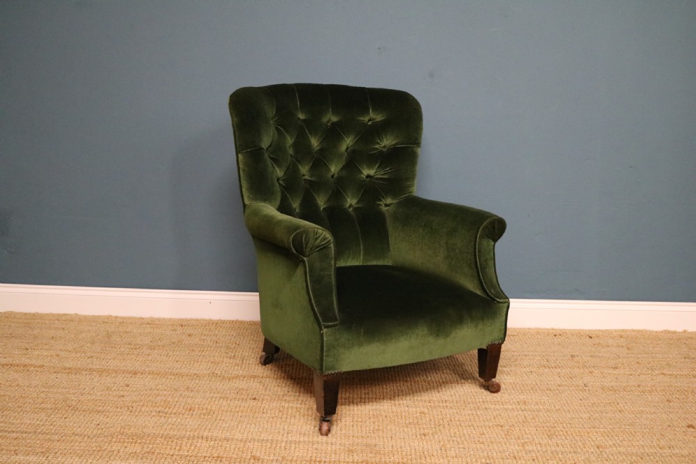 A Victorian armchair upholstered in deep forest green velvet featuring a button-backed backrest and tapered wooden front legs on castors. View III