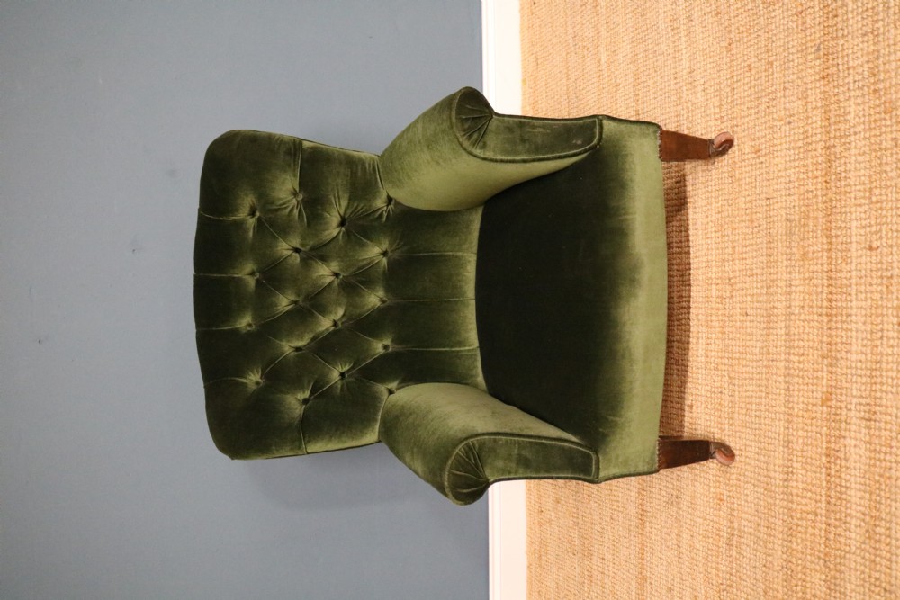 A Victorian armchair upholstered in deep forest green velvet featuring a button-backed backrest and tapered wooden front legs on castors. View IV