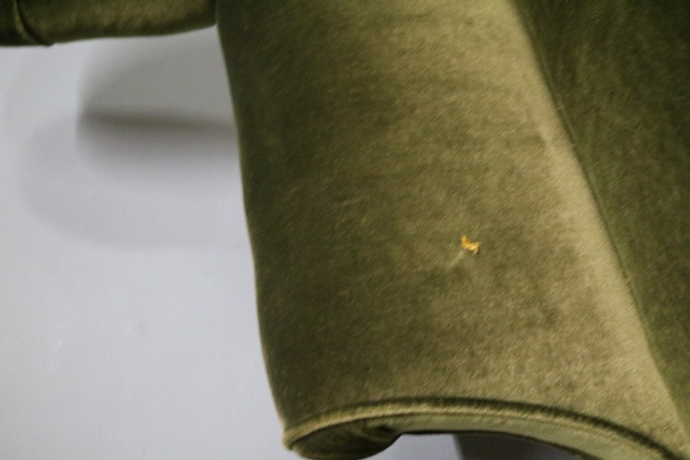 A Victorian armchair upholstered in deep forest green velvet featuring a button-backed backrest and tapered wooden front legs on castors. View VI