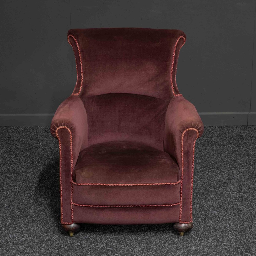 A Victorian armchair upholstered in dark burgundy velvet with braided trim detailing and short turned wooden feet on castors. View II