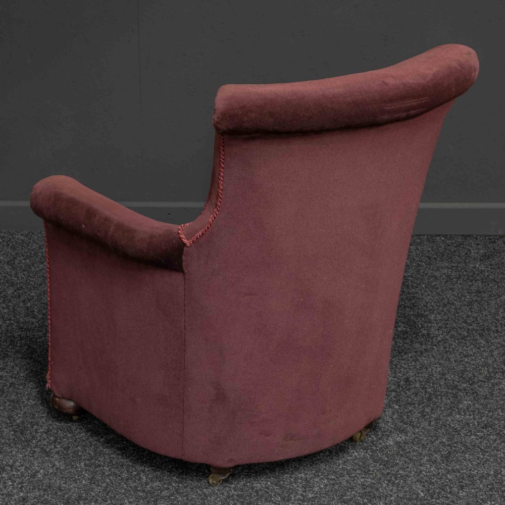 A Victorian armchair upholstered in dark burgundy velvet with braided trim detailing and short turned wooden feet on castors. View VI