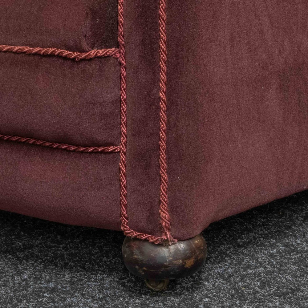 A Victorian armchair upholstered in dark burgundy velvet with braided trim detailing and short turned wooden feet on castors. View VII