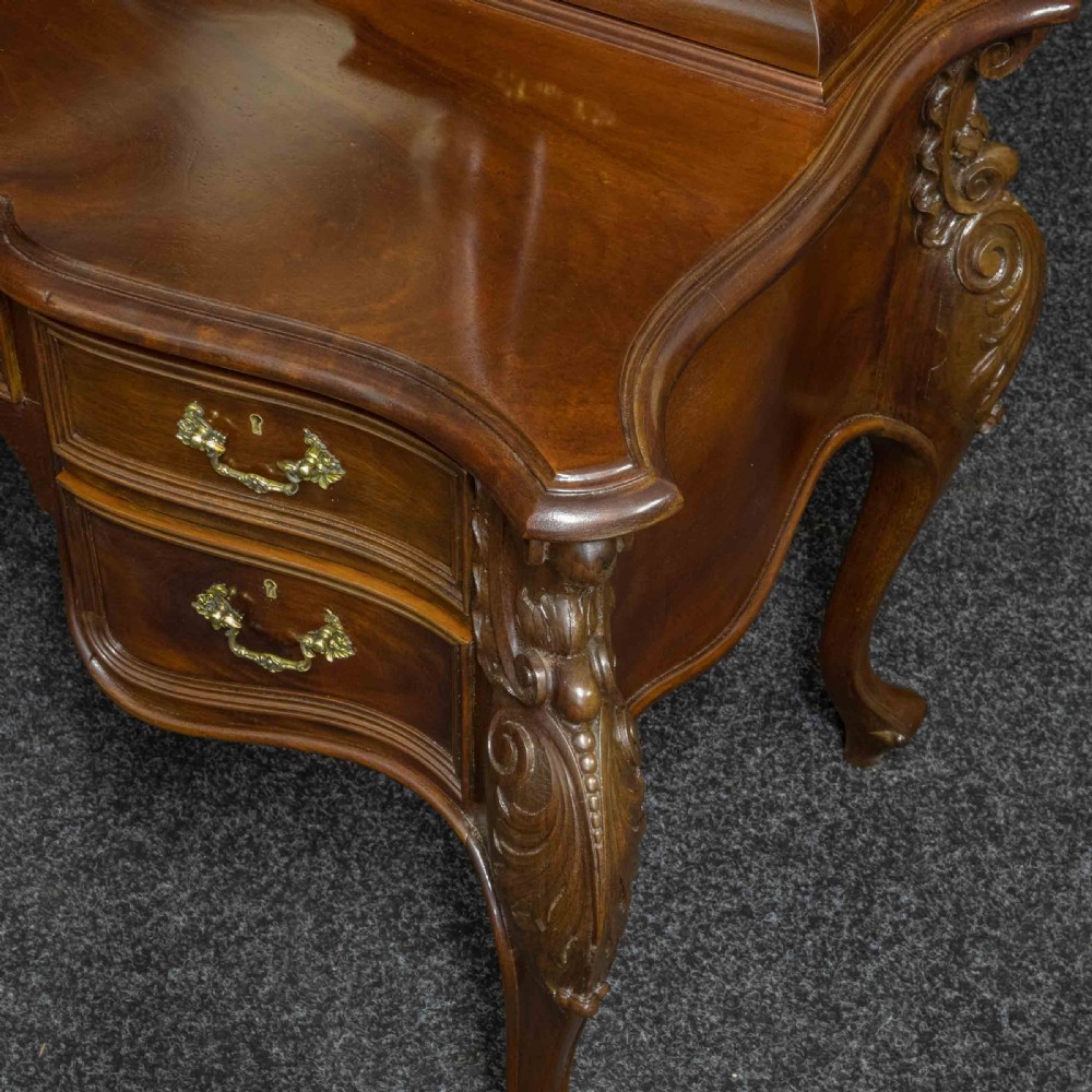 A Victorian carved mahogany dressing table featuring a central swing mirror, small upper jewellery drawers, lower storage drawers, and carved cabriole legs. View IV