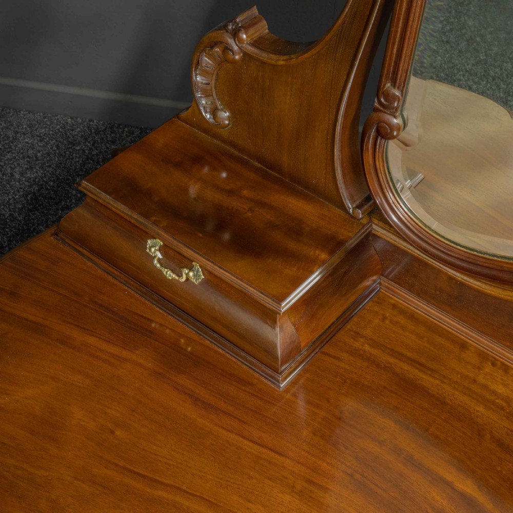A Victorian carved mahogany dressing table featuring a central swing mirror, small upper jewellery drawers, lower storage drawers, and carved cabriole legs. View VII