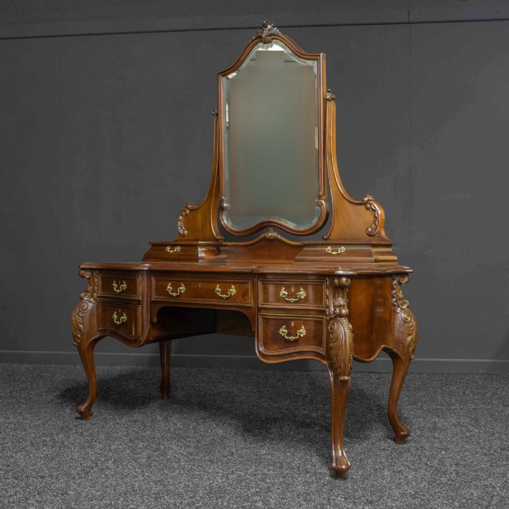 A Victorian carved mahogany dressing table featuring a central swing mirror, small upper jewellery drawers, lower storage drawers, and carved cabriole legs. View IX
