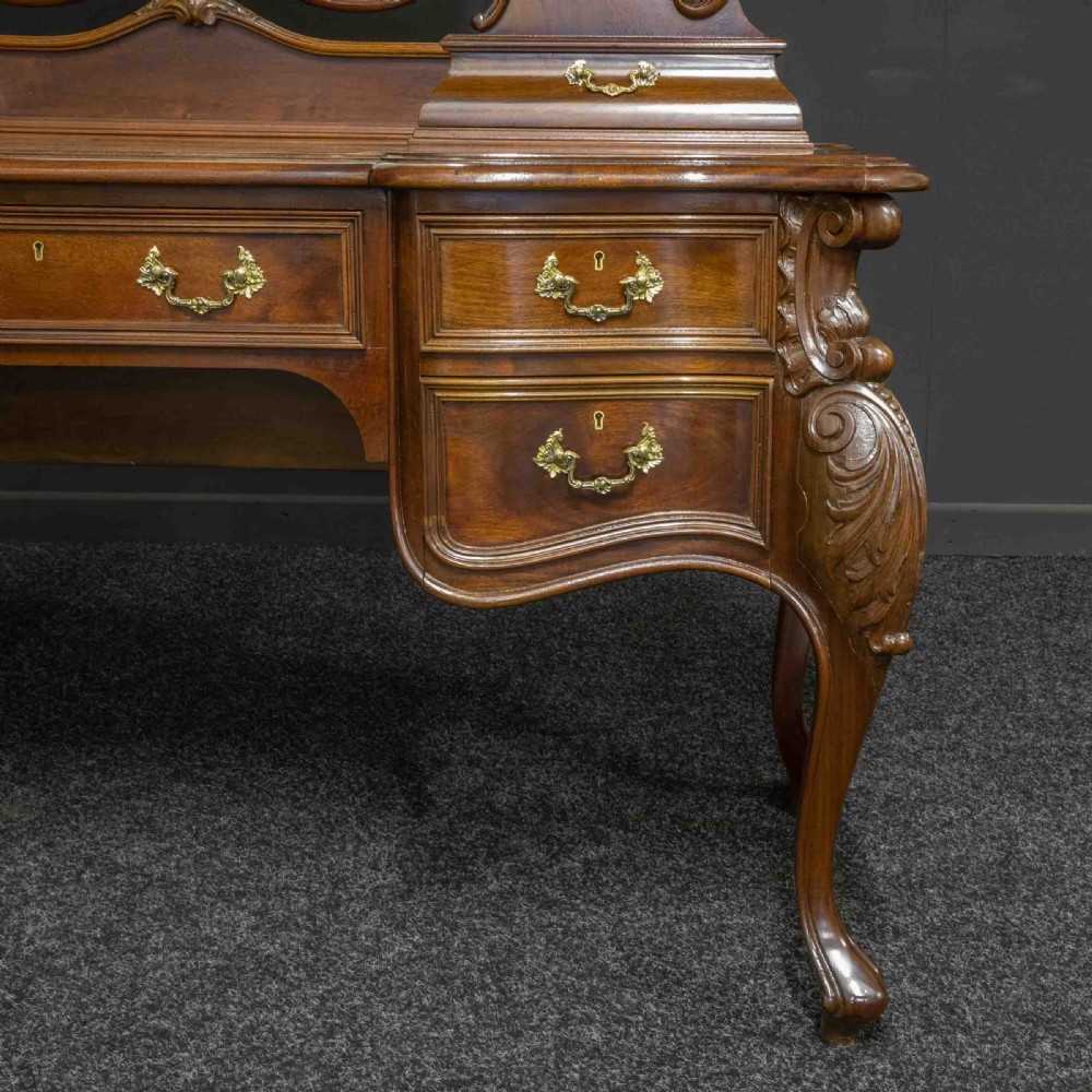 A Victorian carved mahogany dressing table featuring a central swing mirror, small upper jewellery drawers, lower storage drawers, and carved cabriole legs. View X