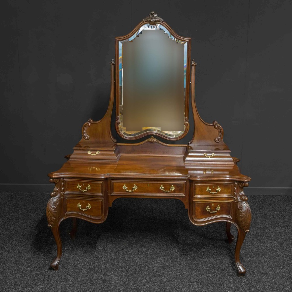 A Victorian carved mahogany dressing table featuring a central swing mirror, small upper jewellery drawers, lower storage drawers, and carved cabriole legs. View XII