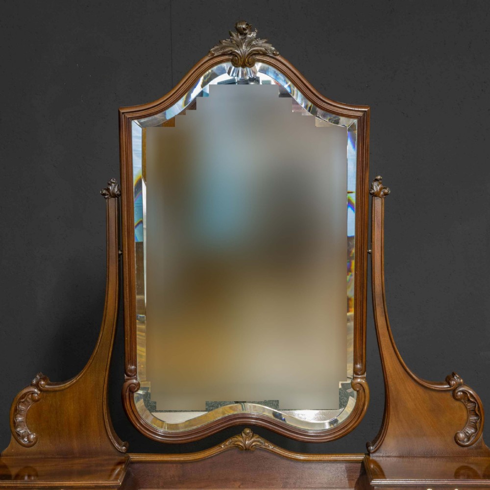 A Victorian carved mahogany dressing table featuring a central swing mirror, small upper jewellery drawers, lower storage drawers, and carved cabriole legs. View XIII