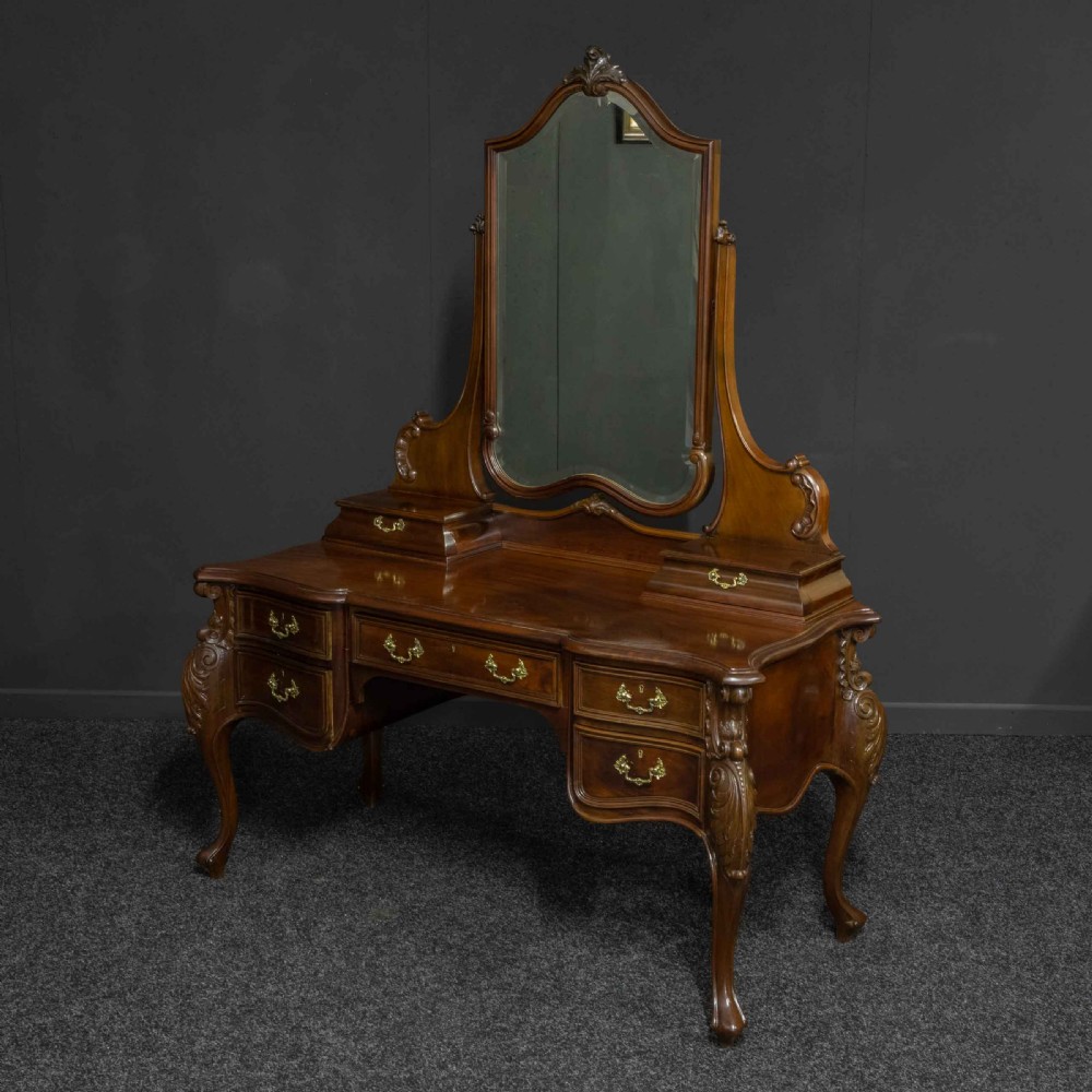 A Victorian carved mahogany dressing table featuring a central swing mirror, small upper jewellery drawers, lower storage drawers, and carved cabriole legs. View XIV