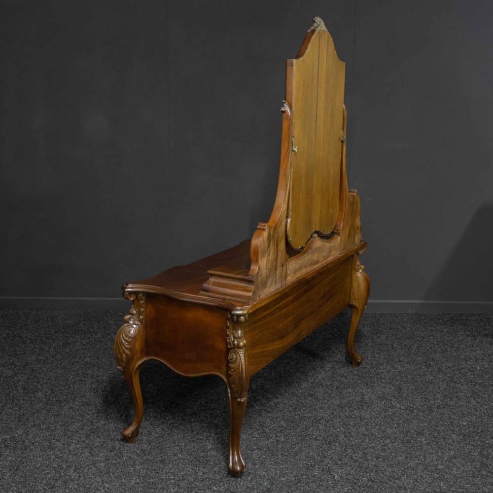 A Victorian carved mahogany dressing table featuring a central swing mirror, small upper jewellery drawers, lower storage drawers, and carved cabriole legs. View XV