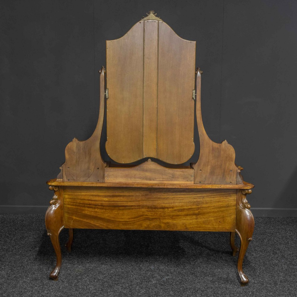 A Victorian carved mahogany dressing table featuring a central swing mirror, small upper jewellery drawers, lower storage drawers, and carved cabriole legs. View XVI