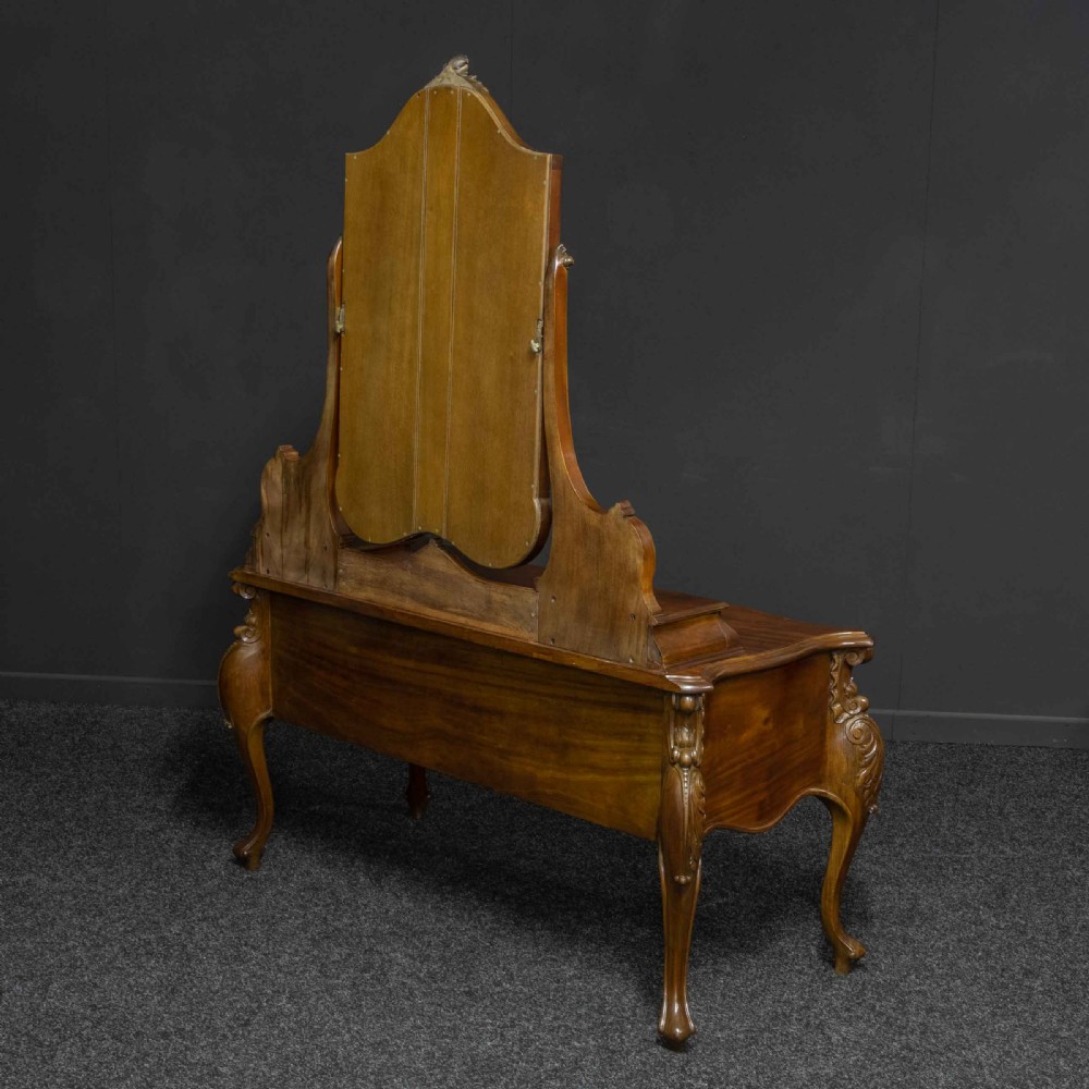 A Victorian carved mahogany dressing table featuring a central swing mirror, small upper jewellery drawers, lower storage drawers, and carved cabriole legs. View XVII