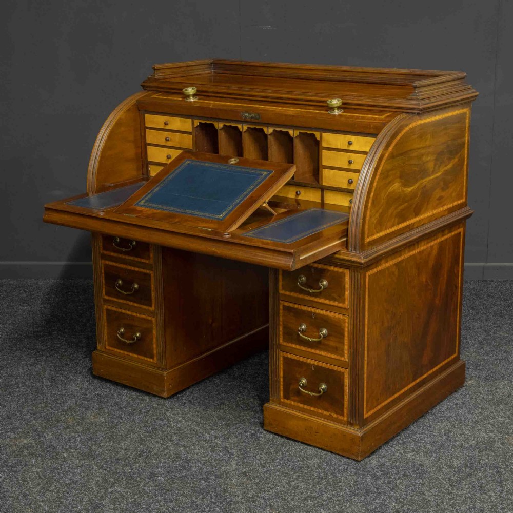 A Sheraton Revival mahogany cylinder desk featuring satinwood crossbanding, twin drawer pedestals, and an extended writing surface fitted with blue leather.