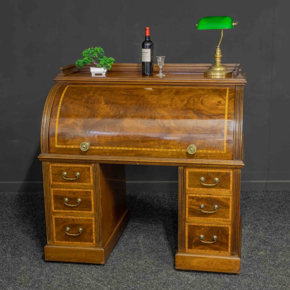 A Sheraton Revival mahogany cylinder desk featuring satinwood crossbanding, twin drawer pedestals, and an extended writing surface fitted with blue leather. View II