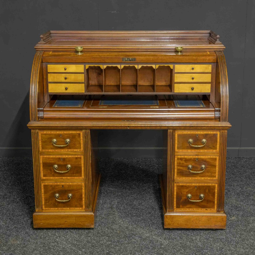 A Sheraton Revival mahogany cylinder desk featuring satinwood crossbanding, twin drawer pedestals, and an extended writing surface fitted with blue leather. View IV