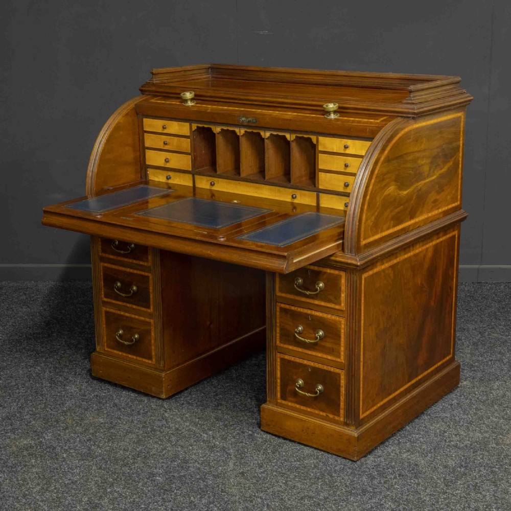 A Sheraton Revival mahogany cylinder desk featuring satinwood crossbanding, twin drawer pedestals, and an extended writing surface fitted with blue leather. View V