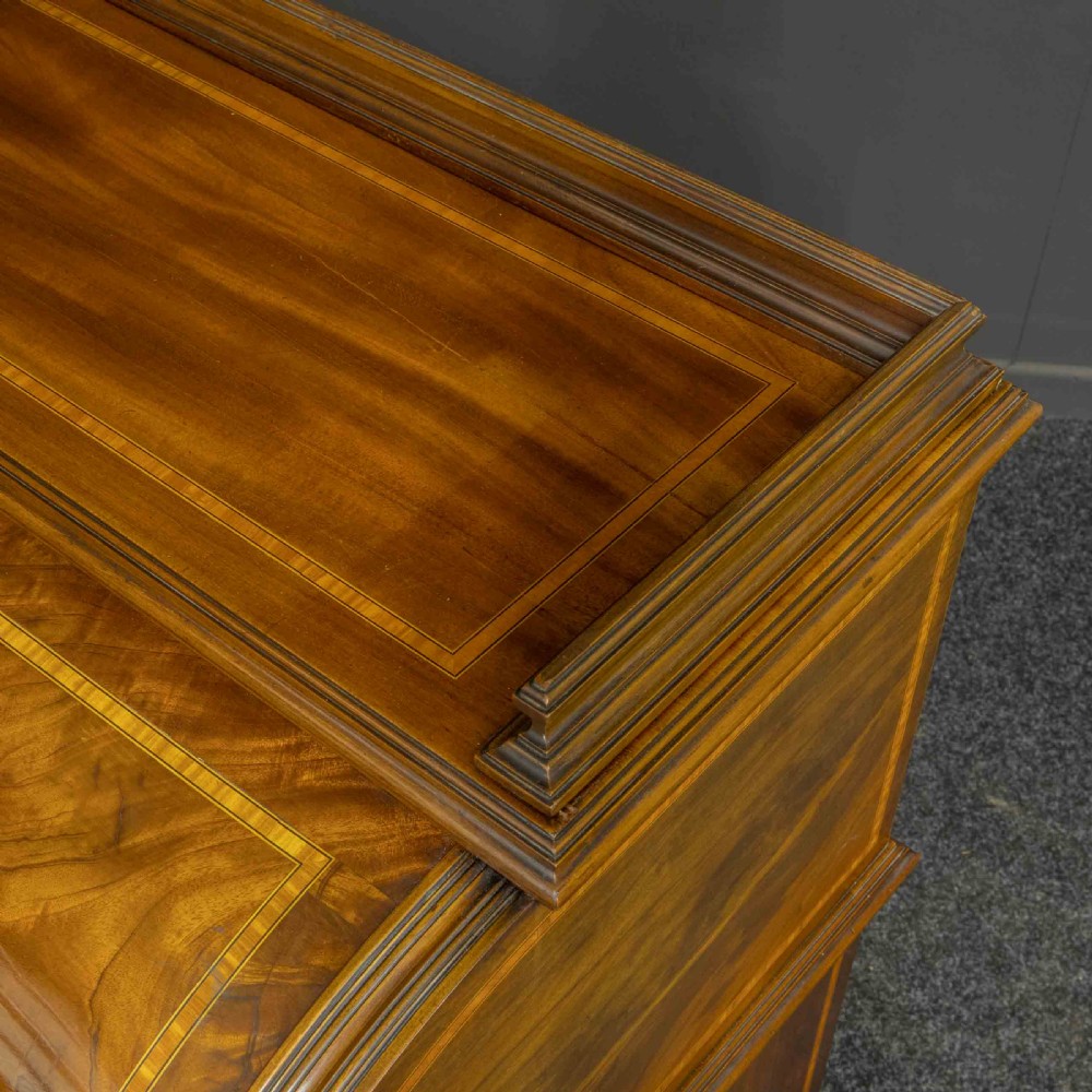 A Sheraton Revival mahogany cylinder desk featuring satinwood crossbanding, twin drawer pedestals, and an extended writing surface fitted with blue leather. View VII