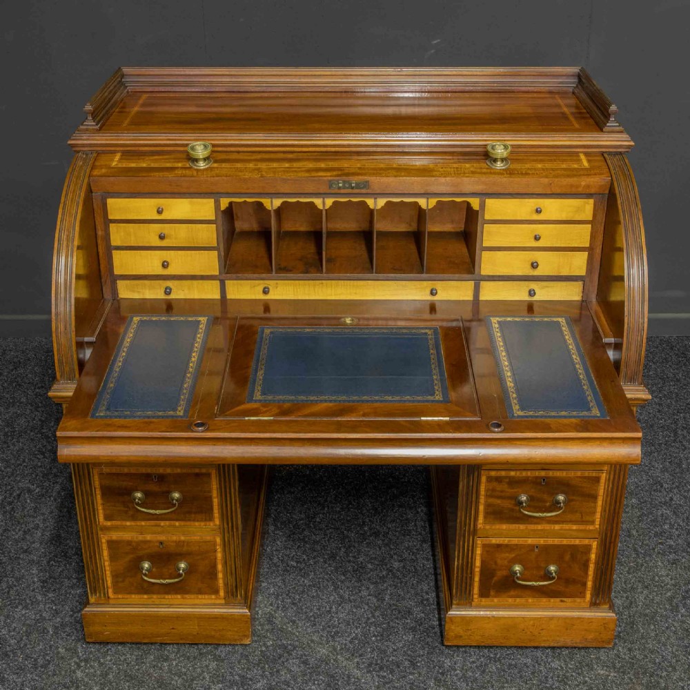 A Sheraton Revival mahogany cylinder desk featuring satinwood crossbanding, twin drawer pedestals, and an extended writing surface fitted with blue leather. View VIII