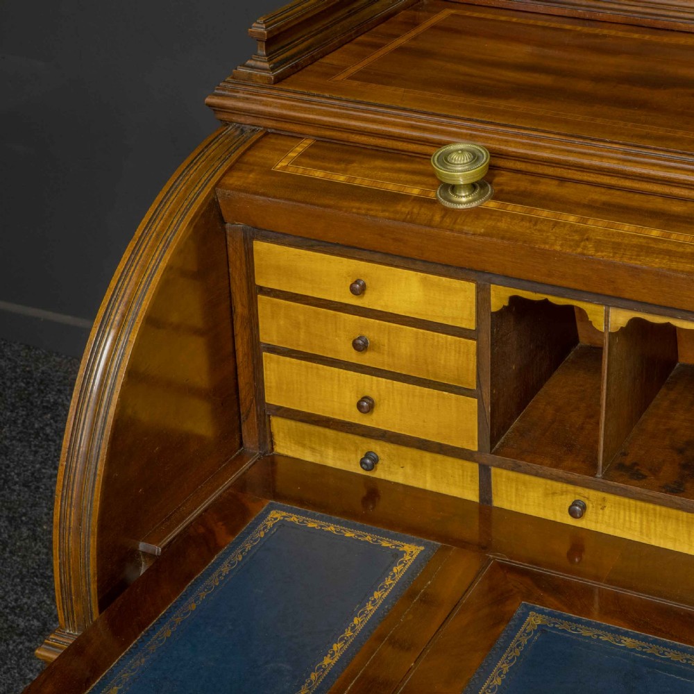A Sheraton Revival mahogany cylinder desk featuring satinwood crossbanding, twin drawer pedestals, and an extended writing surface fitted with blue leather. View X