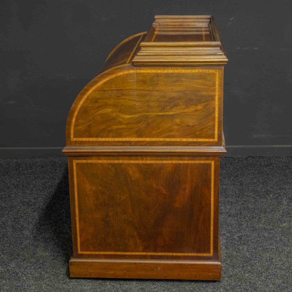 A Sheraton Revival mahogany cylinder desk featuring satinwood crossbanding, twin drawer pedestals, and an extended writing surface fitted with blue leather. View XVIII