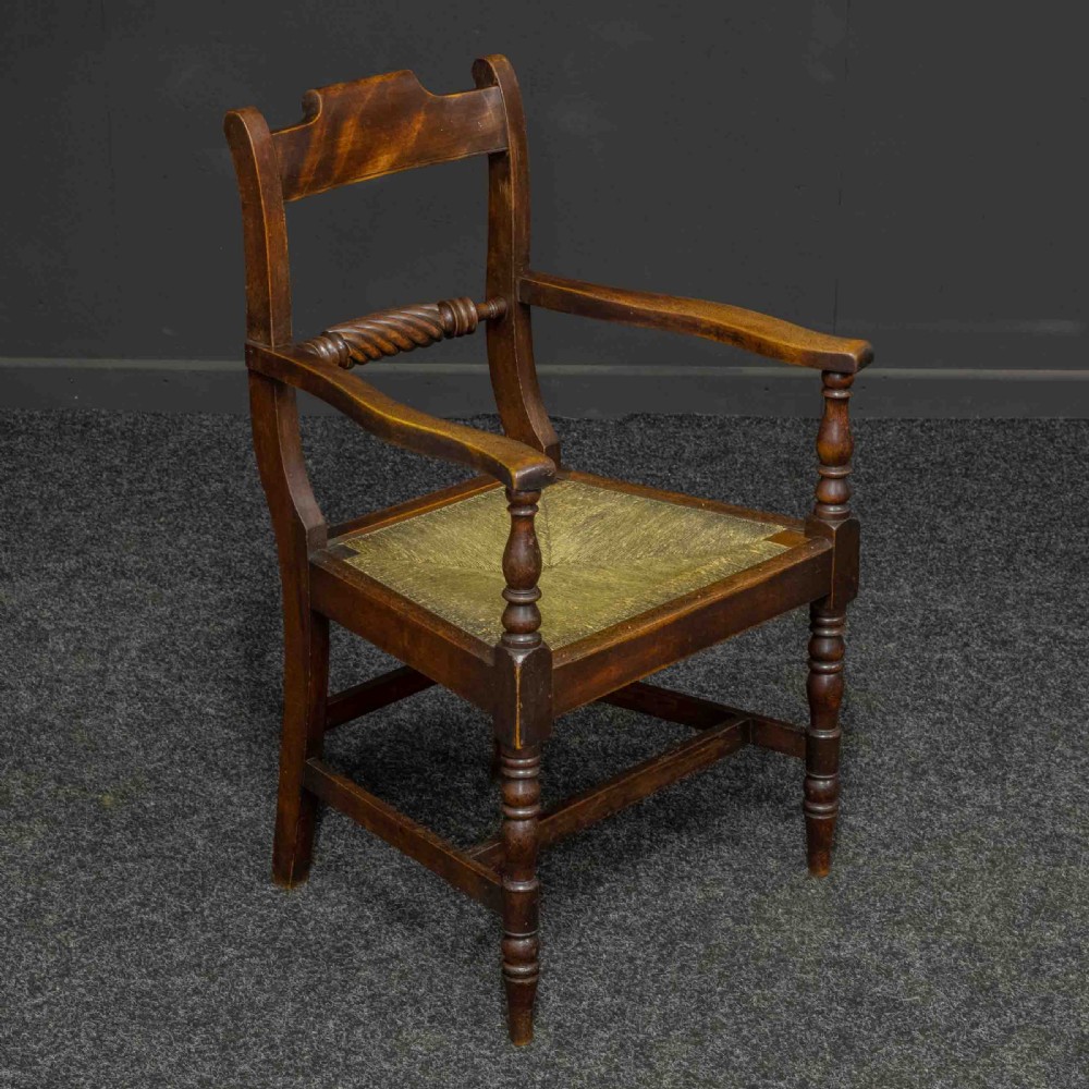 A dark timber provincial Regency armchair featuring a woven rush seat, turned legs, curved arms, and a rope twist back splat. View III