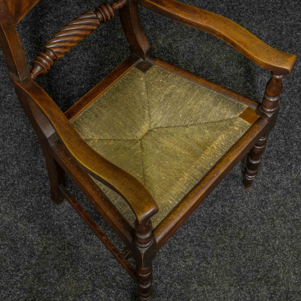 A dark timber provincial Regency armchair featuring a woven rush seat, turned legs, curved arms, and a rope twist back splat. View V