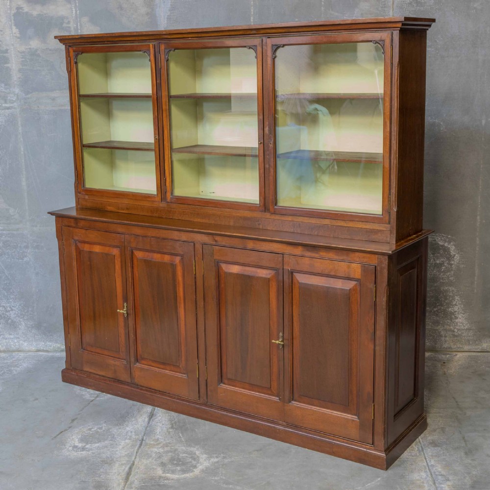 An Edwardian mahogany shop fitting bookcase featuring a three-door glazed upper section with a pale painted interior above a four-door panelled cupboard base.