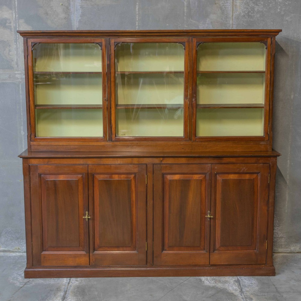 An Edwardian mahogany shop fitting bookcase featuring a three-door glazed upper section with a pale painted interior above a four-door panelled cupboard base. View II