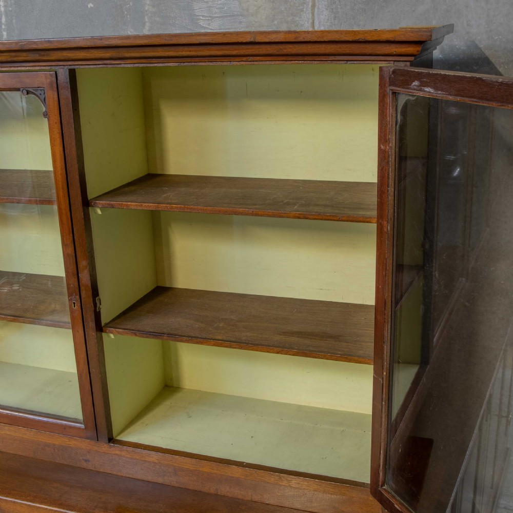 An Edwardian mahogany shop fitting bookcase featuring a three-door glazed upper section with a pale painted interior above a four-door panelled cupboard base. View V