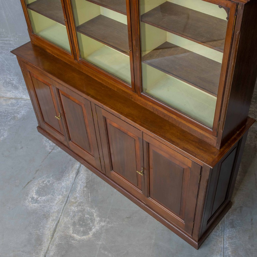 An Edwardian mahogany shop fitting bookcase featuring a three-door glazed upper section with a pale painted interior above a four-door panelled cupboard base. View XII