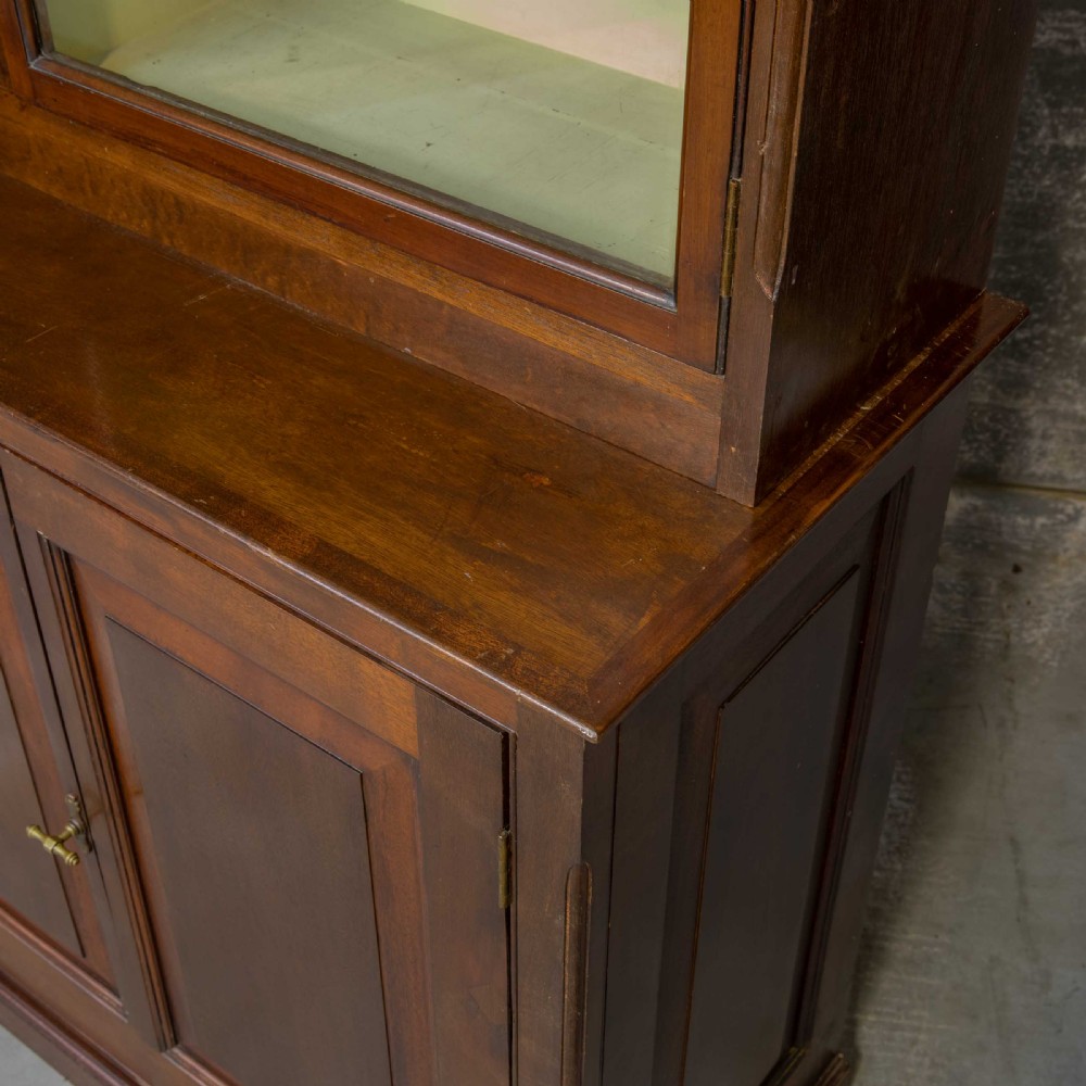 An Edwardian mahogany shop fitting bookcase featuring a three-door glazed upper section with a pale painted interior above a four-door panelled cupboard base. View XIII